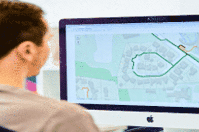 A photograph of a man working on computer, looking at a map