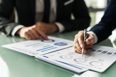 A photograph of people looking at graphs and charts, in a meeting
