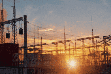 A photo of some electric pylons, with the sun setting behind